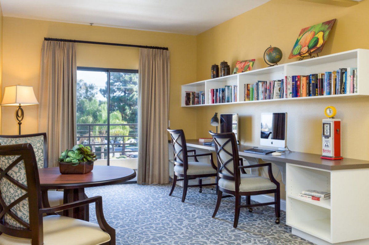 A well-lit home office with dual workstations and a view of greenery outside.