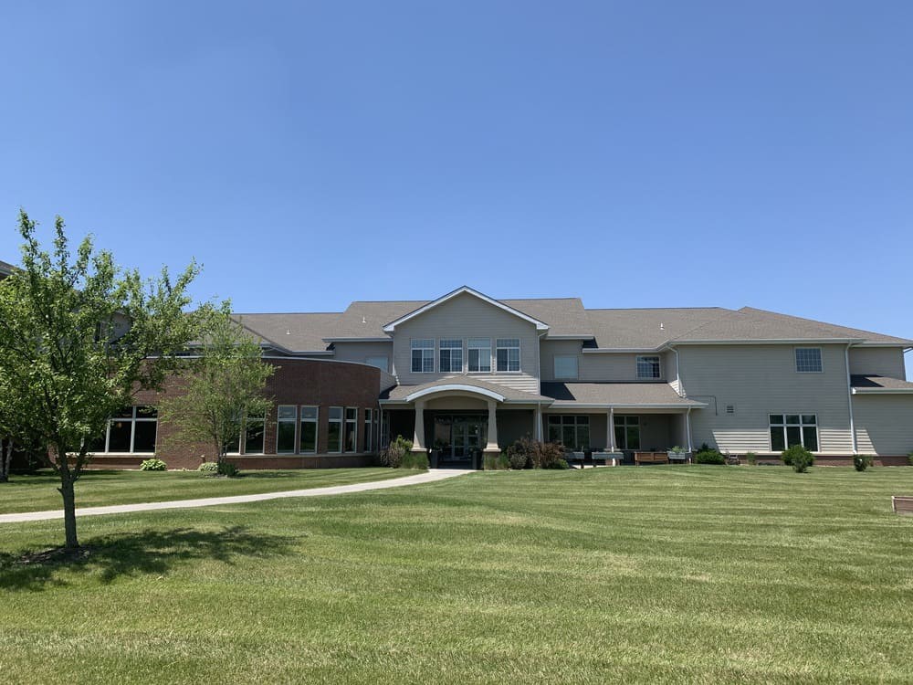 A large suburban house with a spacious lawn under a clear blue sky.