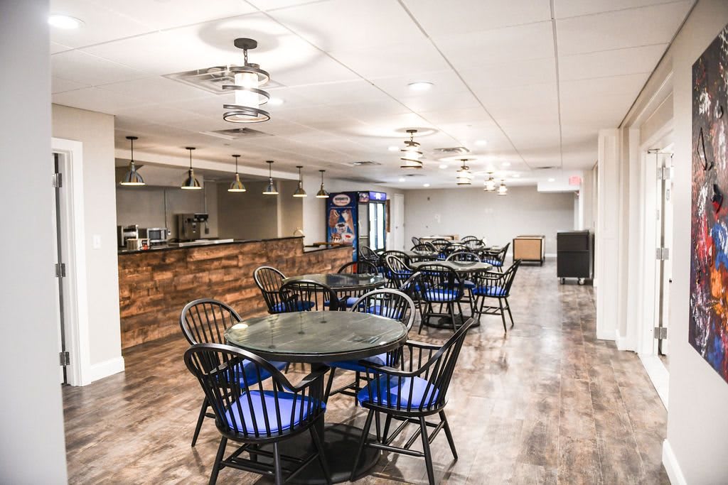 A modern restaurant interior featuring a spacious dining area with tables, chairs, and a wooden bar counter.