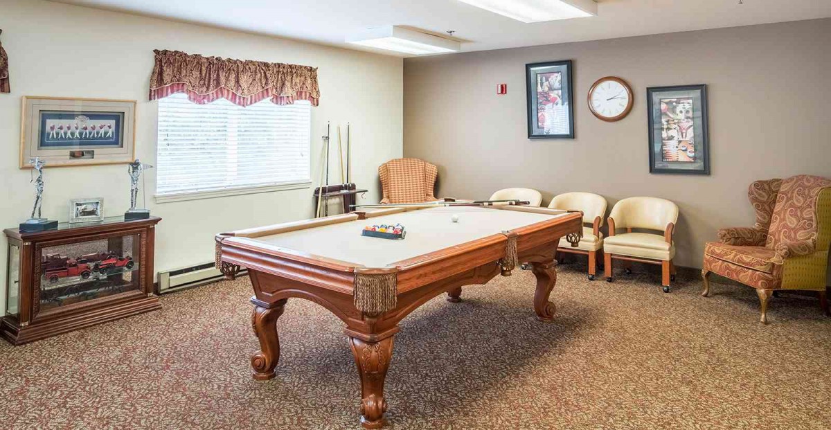 A cozy game room featuring a billiard table surrounded by comfortable seating.