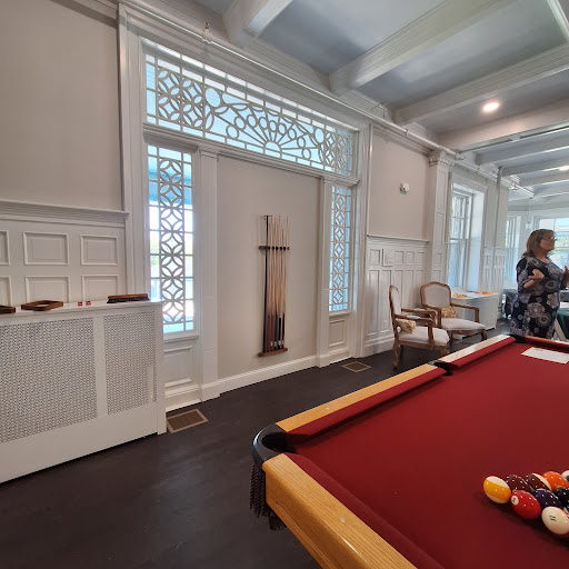 A cozy game room featuring a red pool table, ample natural light, and elegant furnishings.