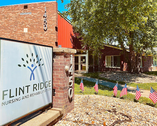 The entrance of a community center with flags and greenery, showcasing the name 'Pinnacle Ridge'.