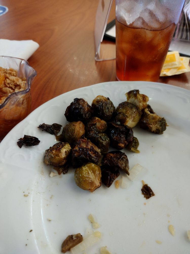 A plate of roasted Brussels sprouts served with a drink.