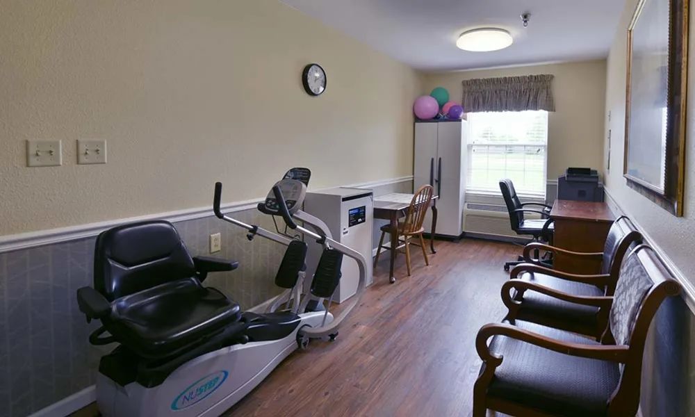 A small fitness room with exercise equipment, tables, and chairs.