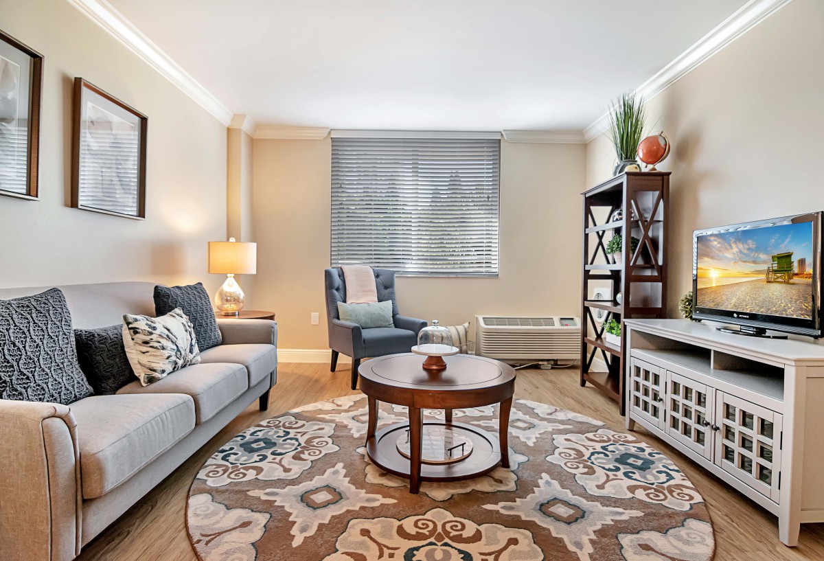 A cozy and well-decorated living room featuring a sofa, coffee table, armchair, rug, and shelving unit.