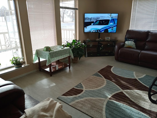A cozy living room featuring a television, comfortable seating, and decorative plants.