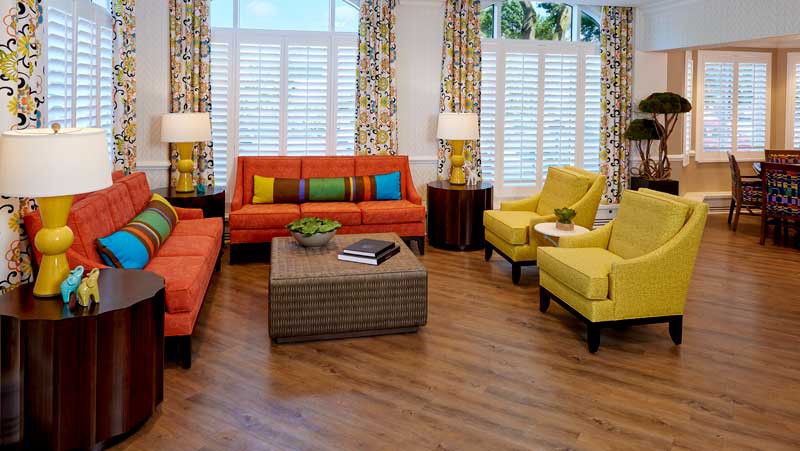 A vibrant living room with colorful sofas, armchairs, and patterned curtains.