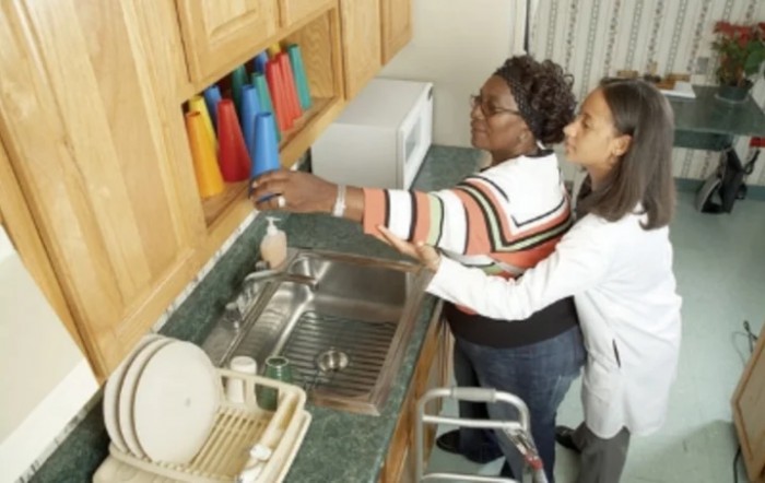 A caregiver assisting an elderly person in the kitchen.
