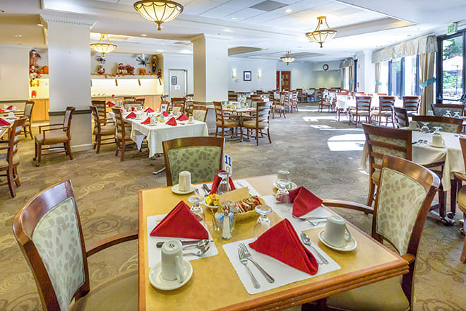 A well-arranged dining area with neatly set tables and red napkins.