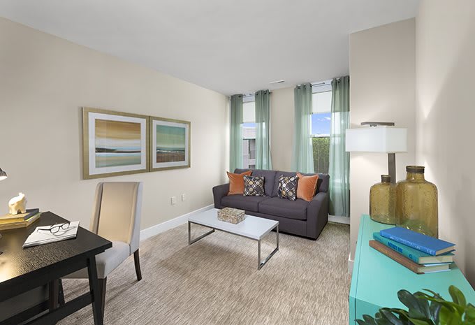 A modern living room with a gray sofa, decorative pillows, and contemporary artwork on the wall.