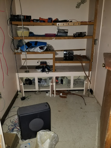 A cluttered storage room with shelves and scattered electronics.