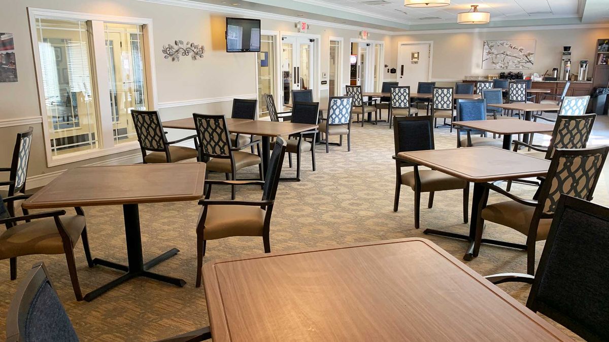 An empty dining area with neatly arranged tables and chairs, featuring a carpeted floor and elegant interior design.