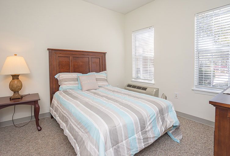 A cozy bedroom with a bed featuring striped bedding and a window letting in natural light.