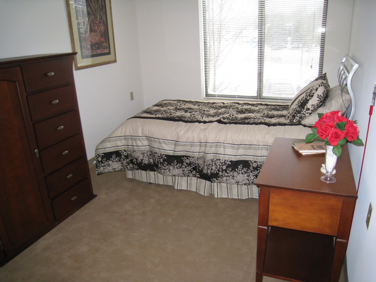 A tidy bedroom with a bed, dresser, and window.
