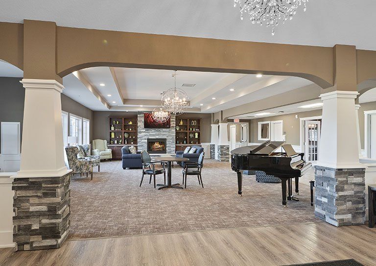 A luxurious and spacious living room featuring a grand piano, elegant chandeliers, and a cozy fireplace.