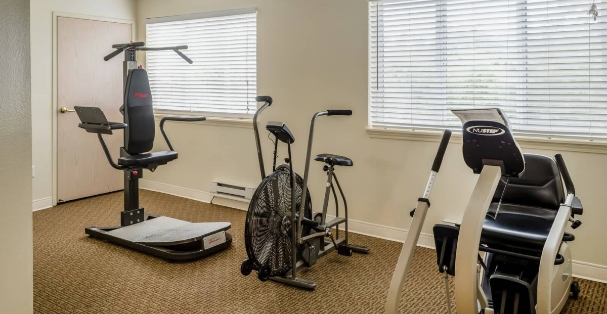 A small indoor gym with various exercise equipment, including a stationary bike and treadmill.