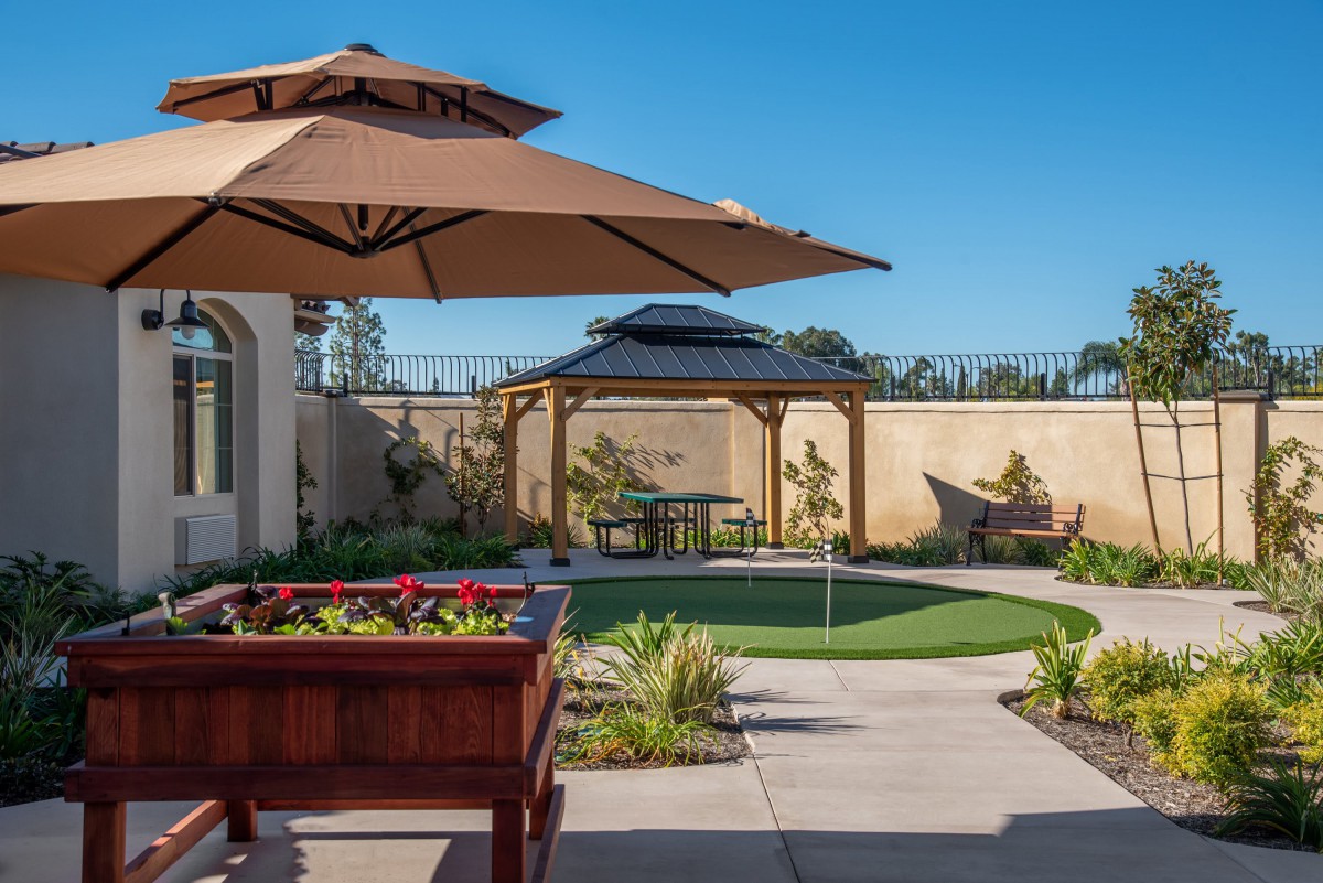 A beautifully landscaped backyard with a patio, outdoor furniture, and a gazebo.
