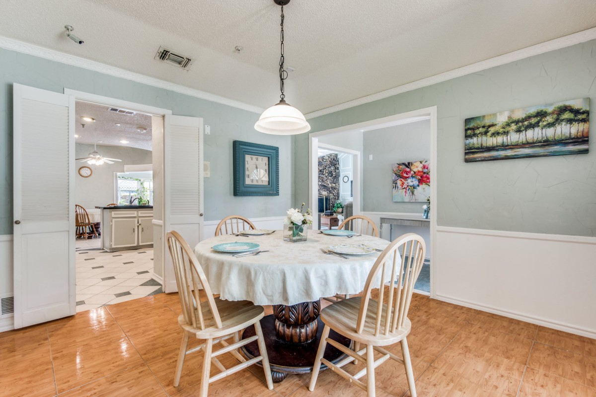 A cozy dining area with a round table and wooden chairs, highlighted by a central light fixture.