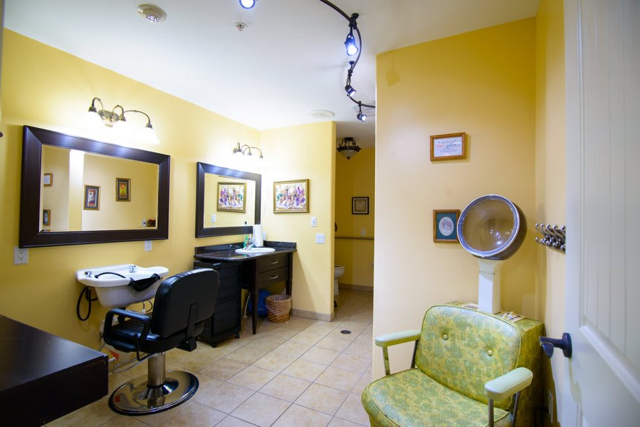 A cozy hair salon with yellow walls, equipped with styling chairs and mirrors.