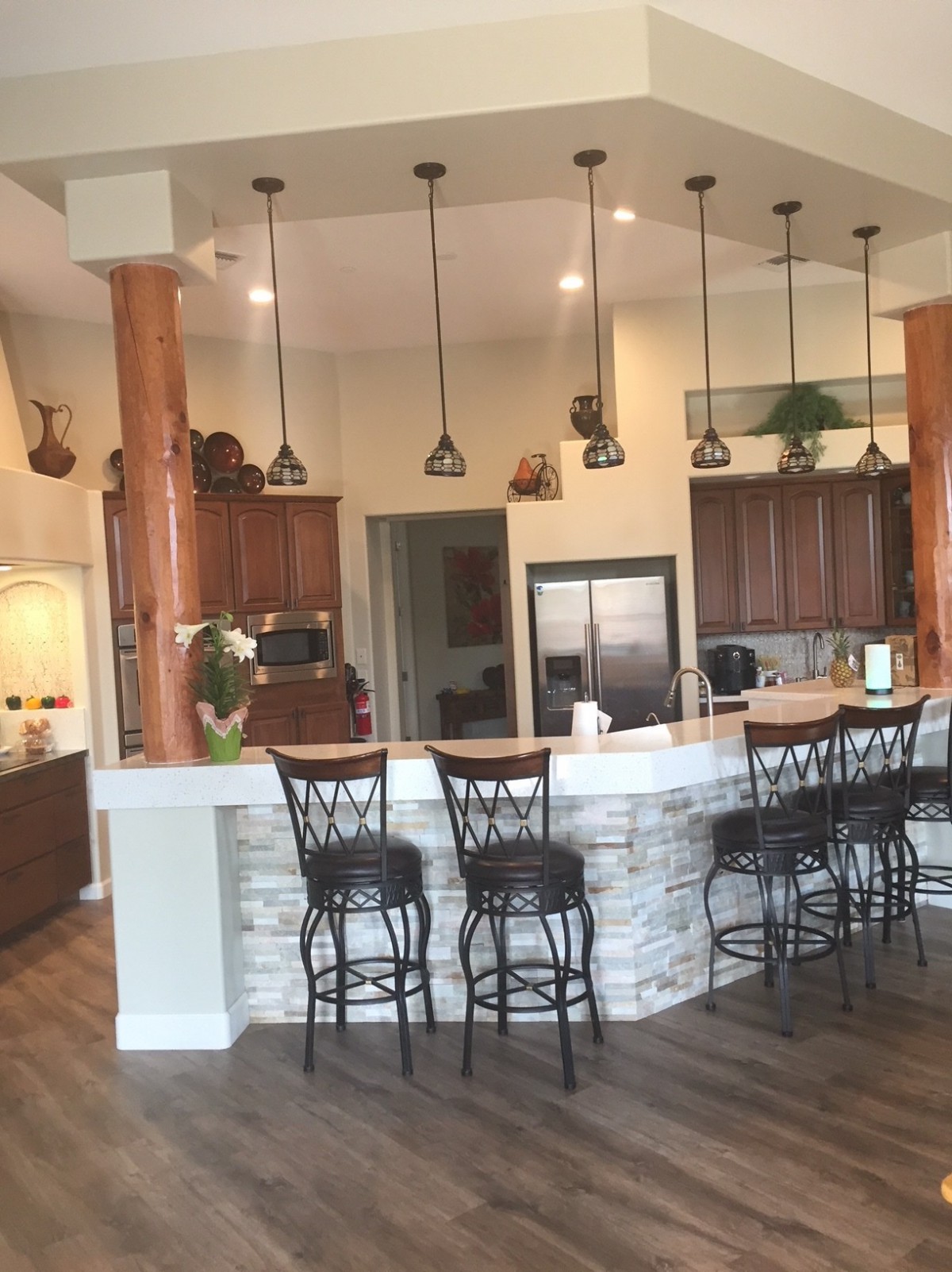 A modern kitchen with an open concept featuring a stone counter bar area and elegant pendant lighting.