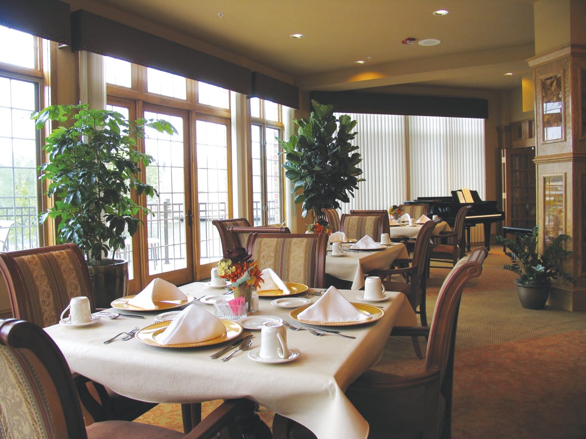 A cozy restaurant dining area set for guests, featuring elegant decor and large windows.