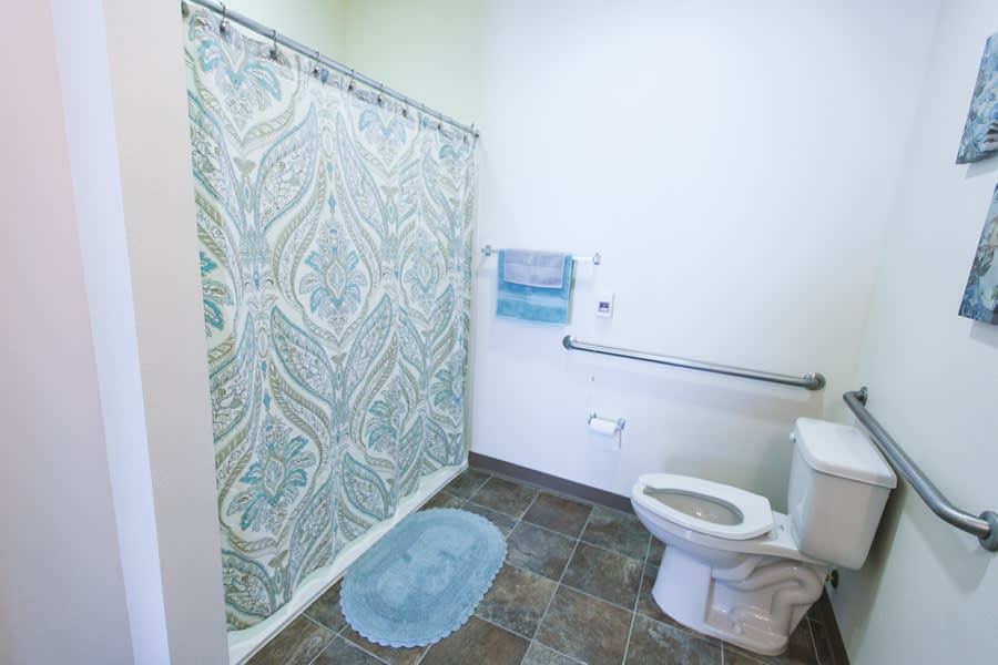 A clean, modern bathroom with a toilet, shower curtain, and tile floor.