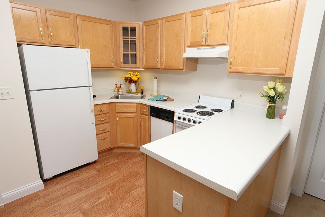 A modern kitchen with light wooden cabinets and white appliances.