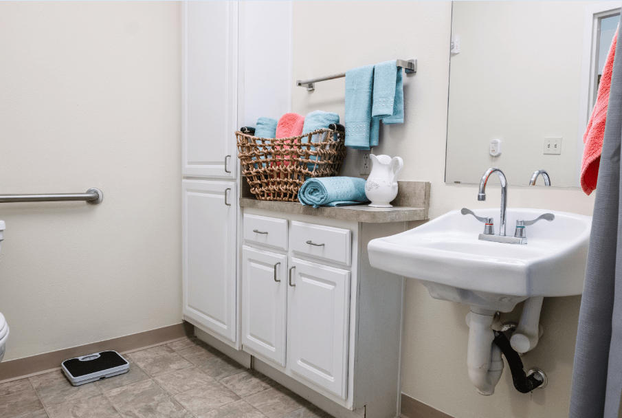 A clean and organized bathroom with white cabinets and blue towels.