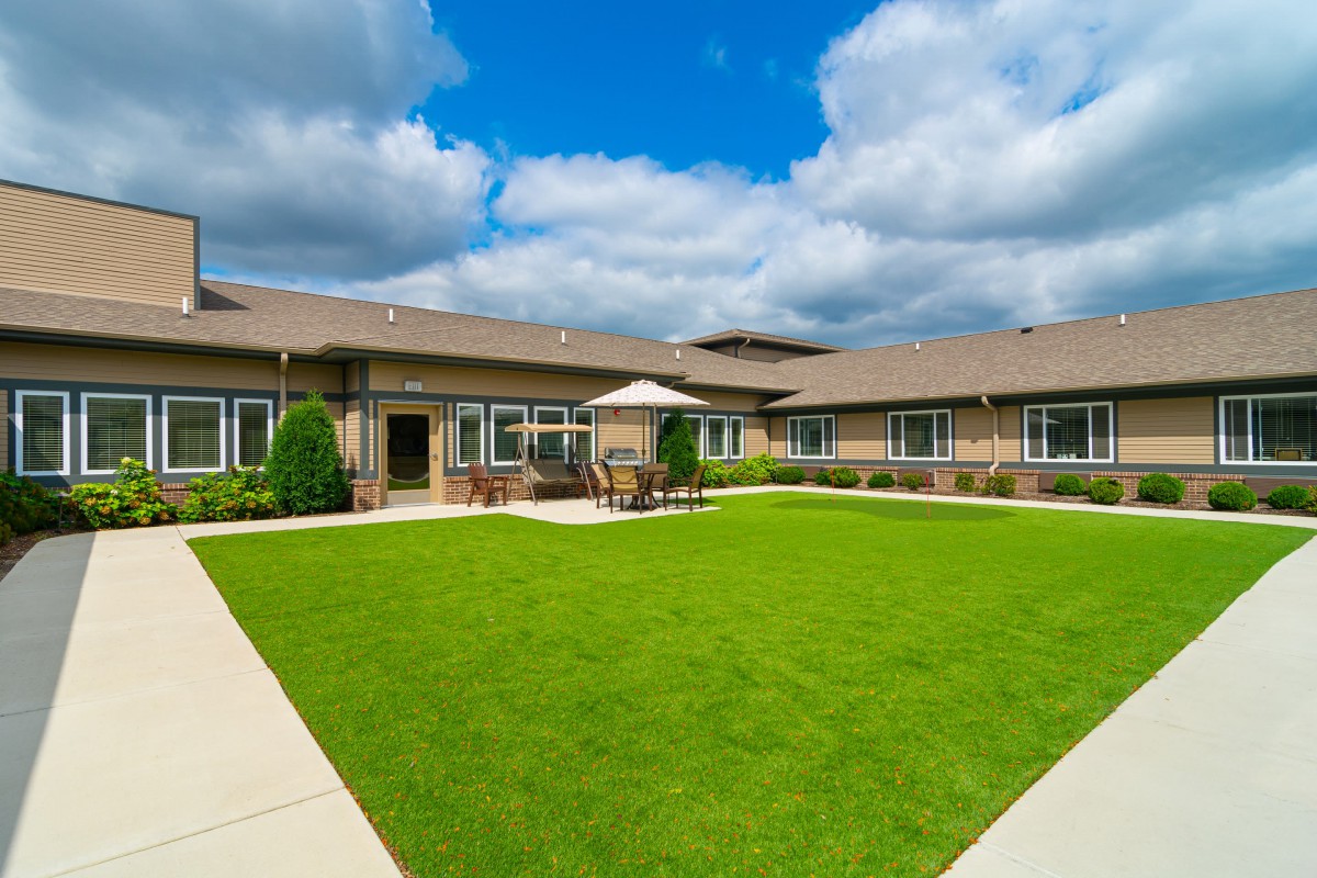 A spacious courtyard with a well-maintained lawn surrounded by a modern building under a partly cloudy sky.