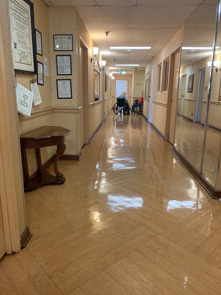 A polished hallway with a wheelchair at the end and framed items on the walls.