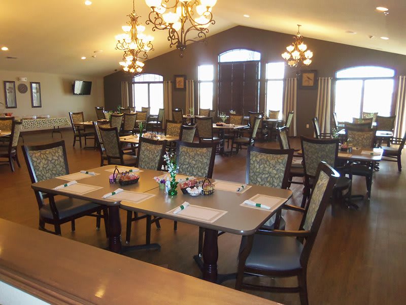 A spacious dining area with neatly arranged tables and elegant chandeliers.