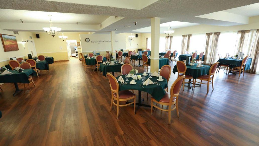 A spacious dining area with neatly set tables and chairs on a wooden floor.