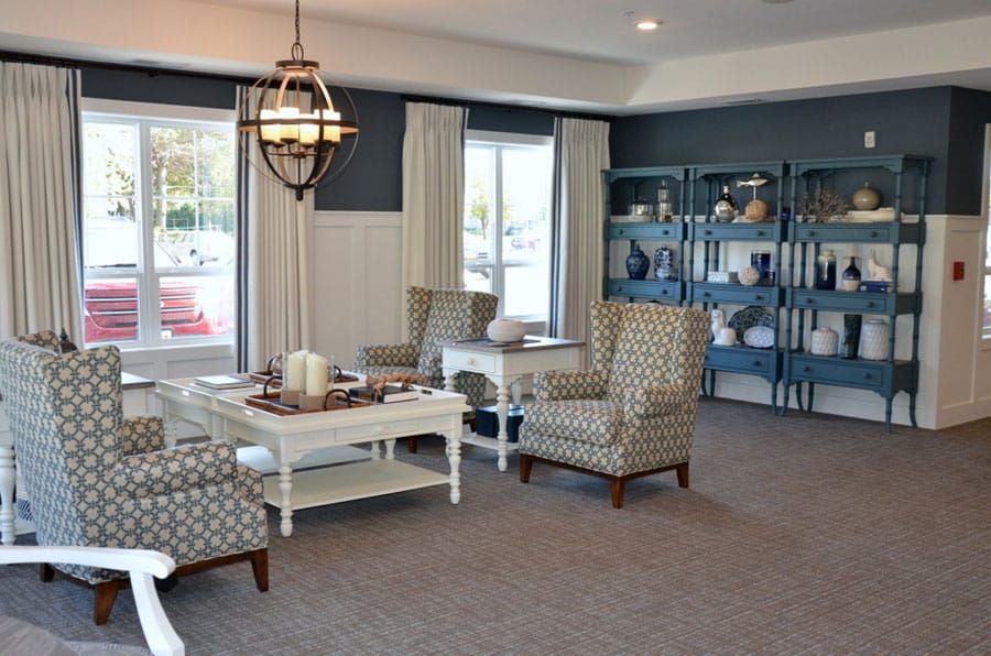 A modern living room with patterned chairs, a white table, and a bookshelf.