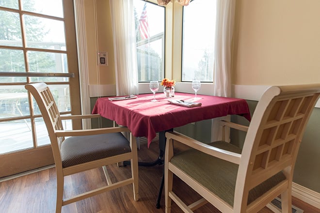 Cozy dining area with a table set for two near bright windows.