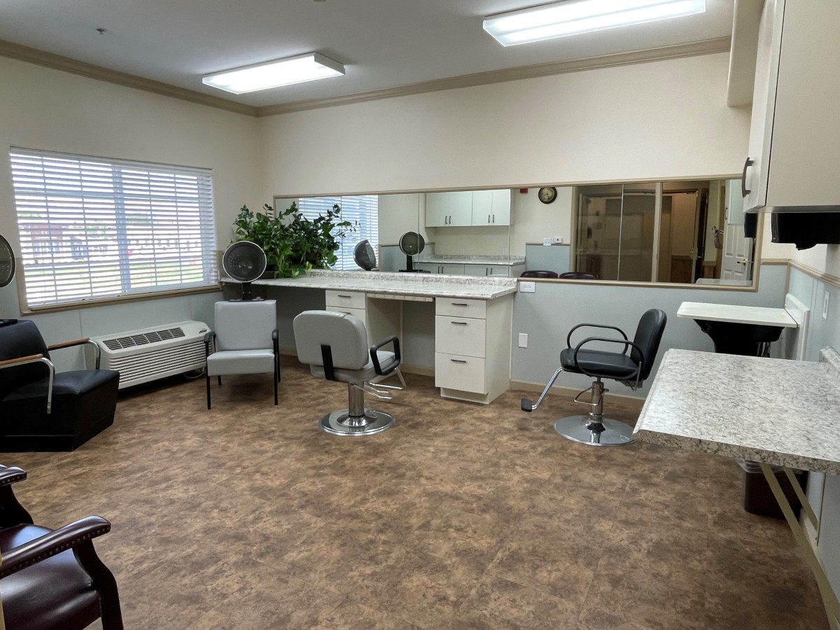 An empty hair salon with chairs, mirrors, and bright lighting.