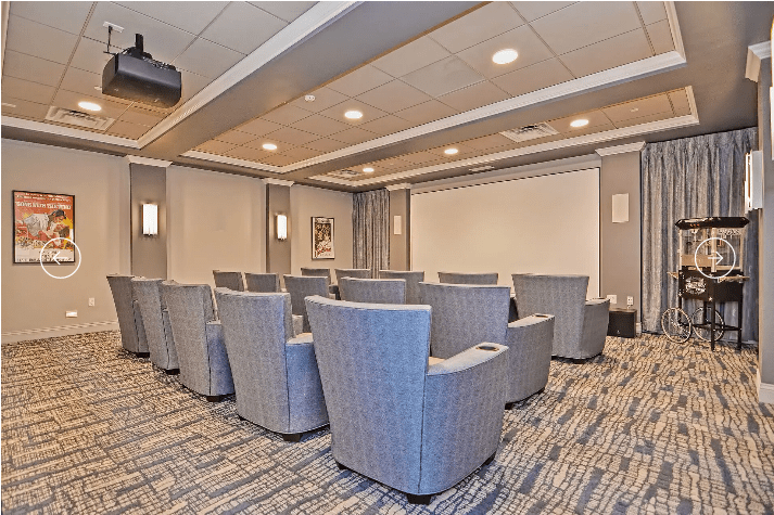 A small theater-style conference room with comfortable seating and a projector screen.