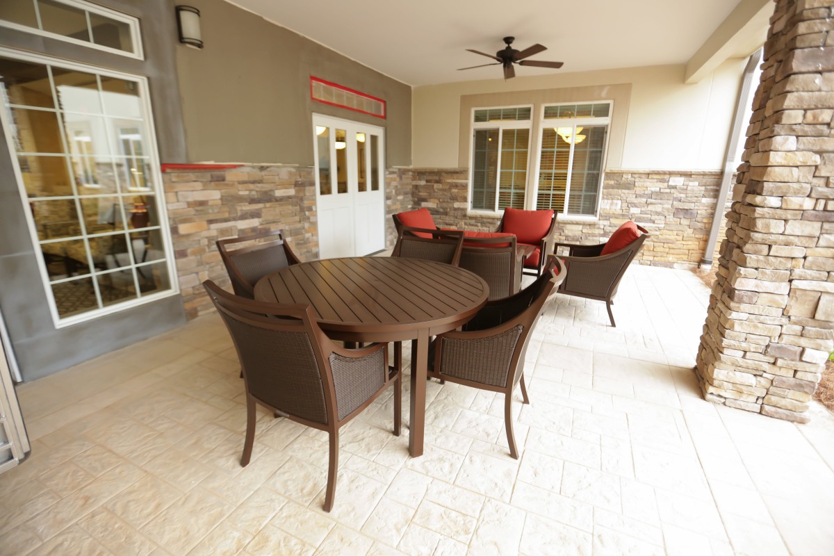 A spacious patio featuring a rattan outdoor seating set with a table and chairs, under a ceiling fan.