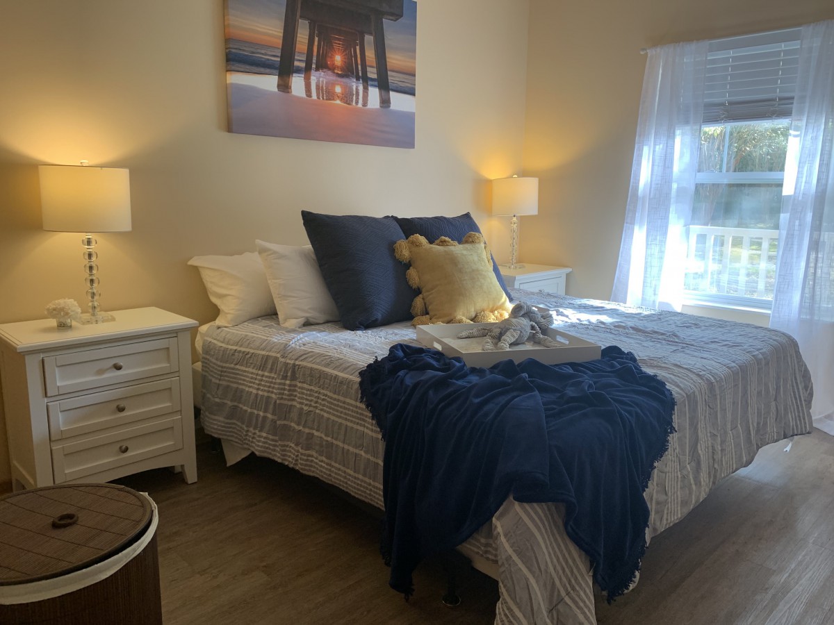 Cozy bedroom with a neatly arranged bed, decorative pillows, and soft lighting.