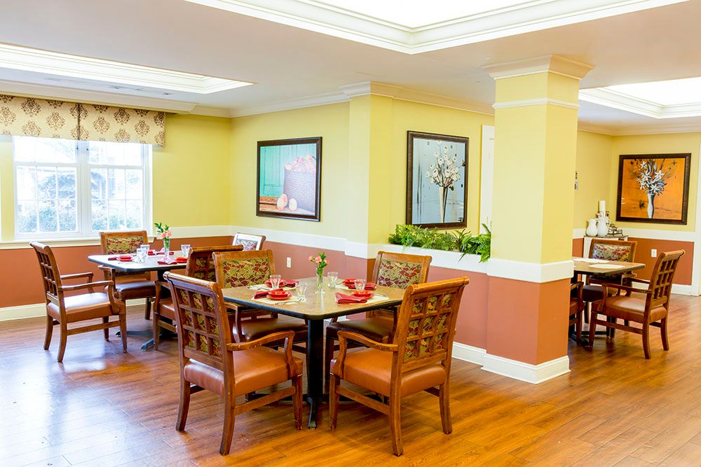 A well-lit dining area with wooden tables and chairs, featuring tasteful decor and artwork on the walls.