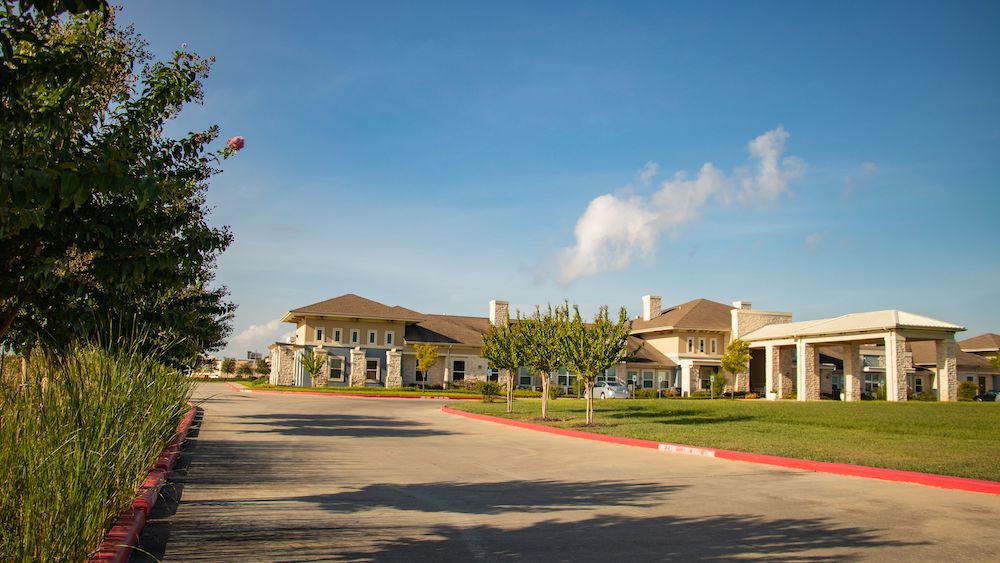 A spacious residential building with a large driveway and well-maintained landscape.