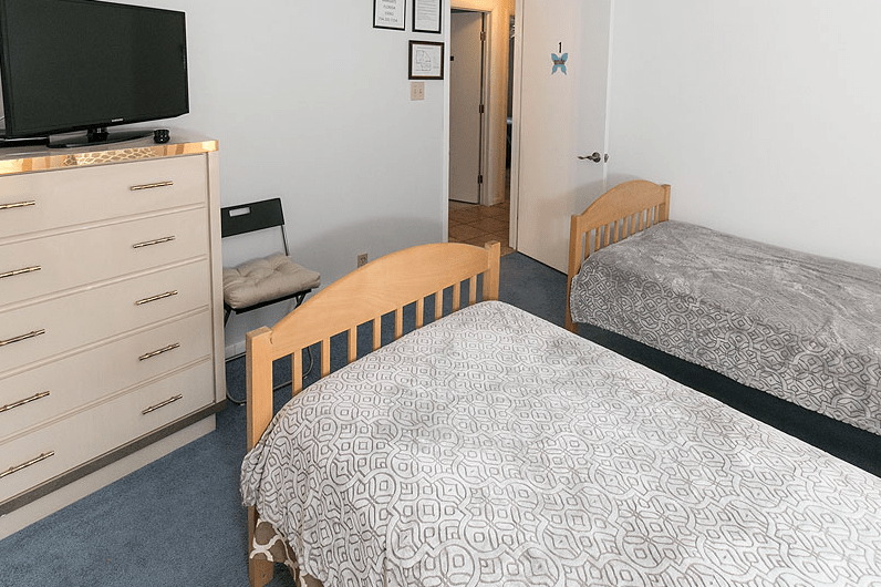 A cozy bedroom with two beds, a dresser, and a television.