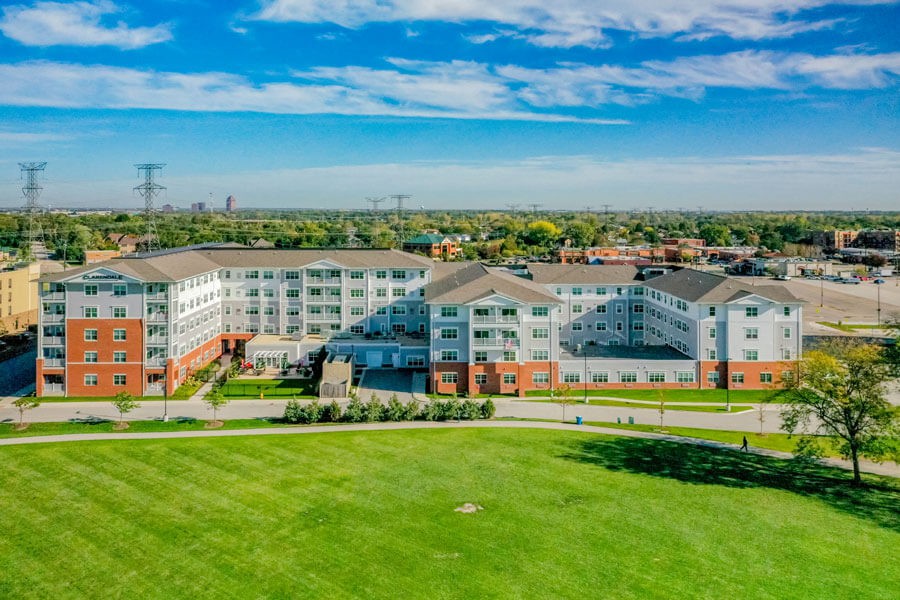 Aerial view of a large residential complex with green lawns under a clear blue sky.
