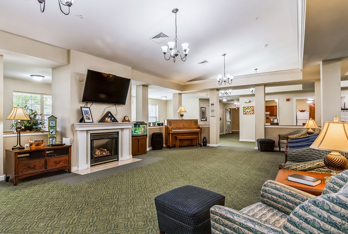 A cozy living area featuring a fireplace, television, and piano, with comfortable seating and warm lighting.