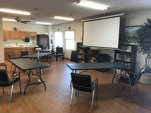 A meeting room equipped with tables, chairs, and a projector screen.