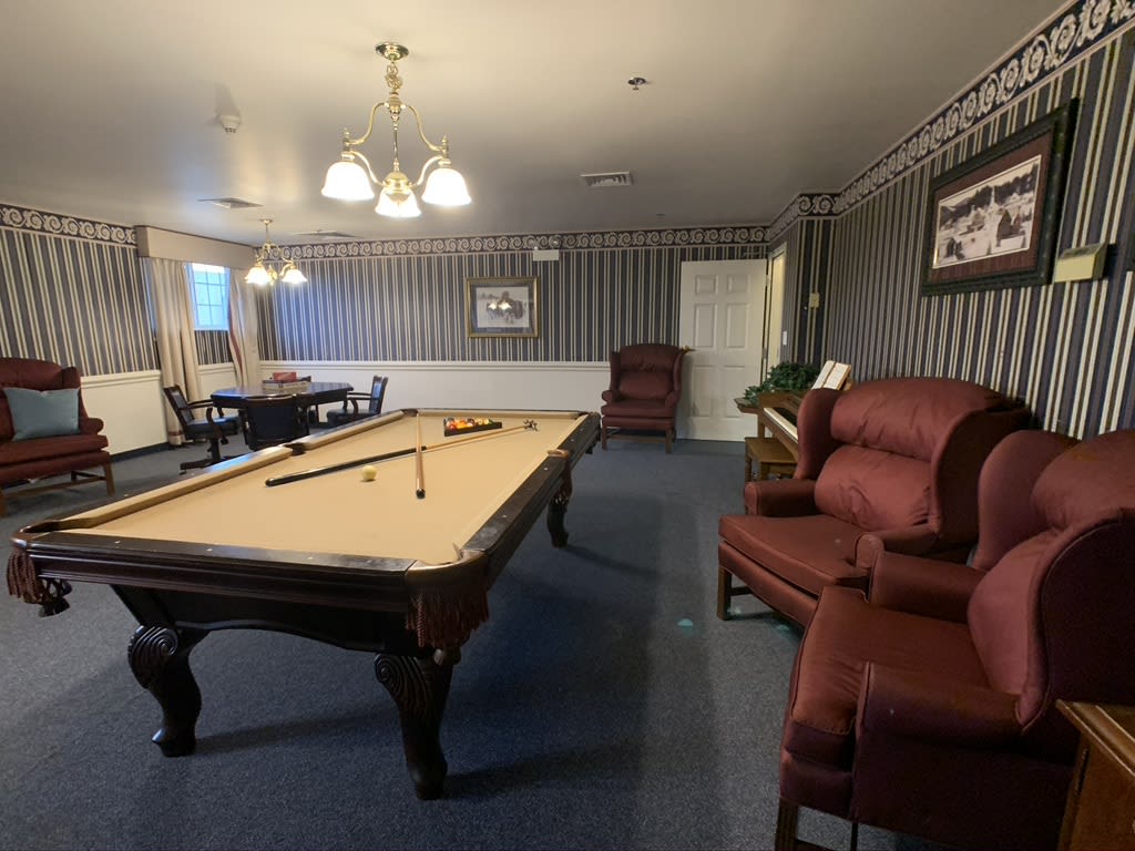 A cozy indoor billiard room with a pool table and comfortable seating.