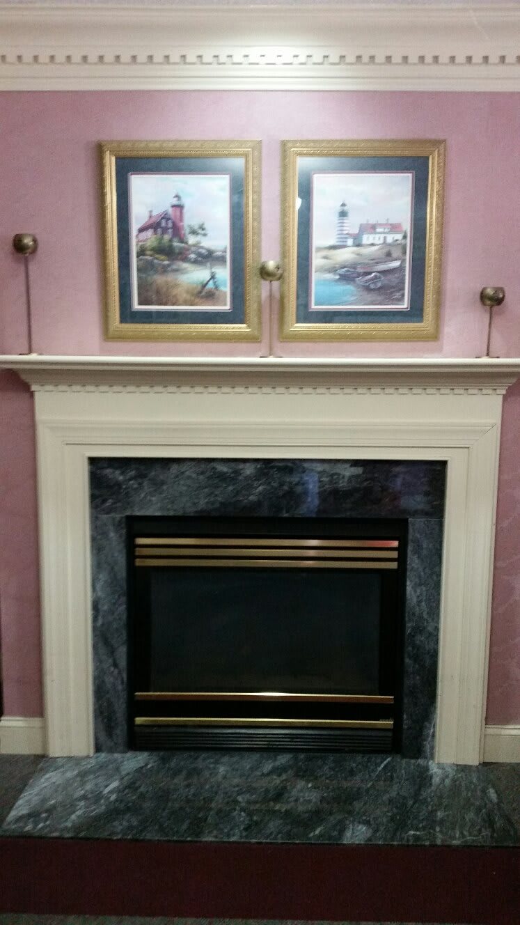 A traditional fireplace with a decorative mantel adorned with framed artwork.