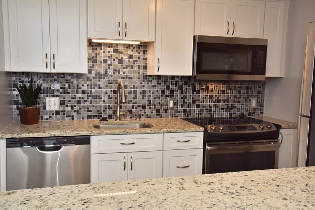 Modern kitchen with granite countertops and mosaic tile backsplash.