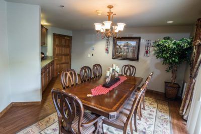 A well-decorated dining room featuring a wooden table and chairs, illuminated by a chandelier.