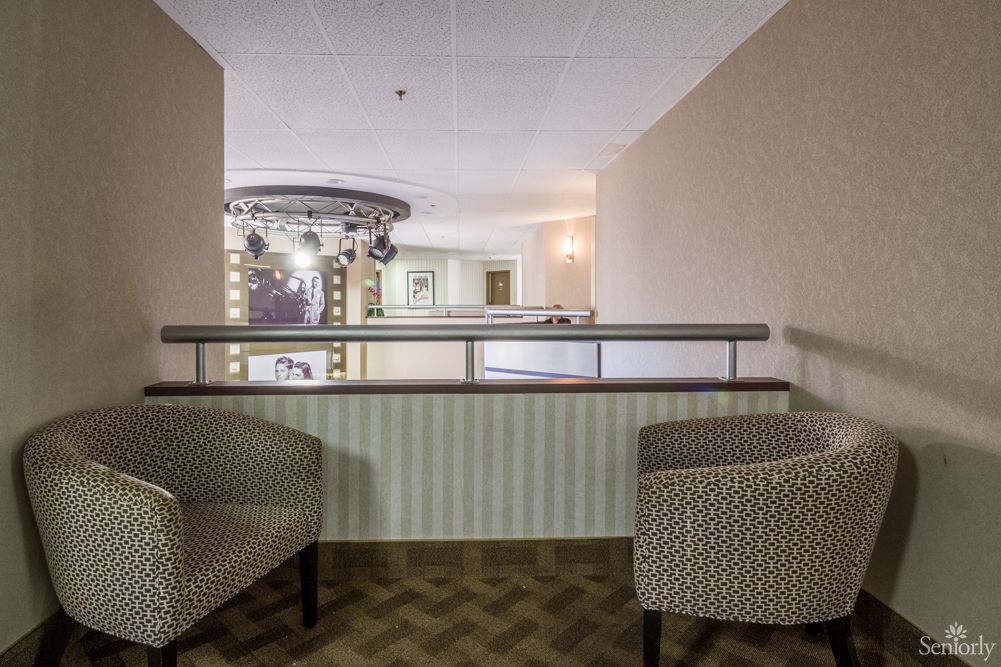 A cozy interior with two patterned chairs and a view of the hallway balcony.