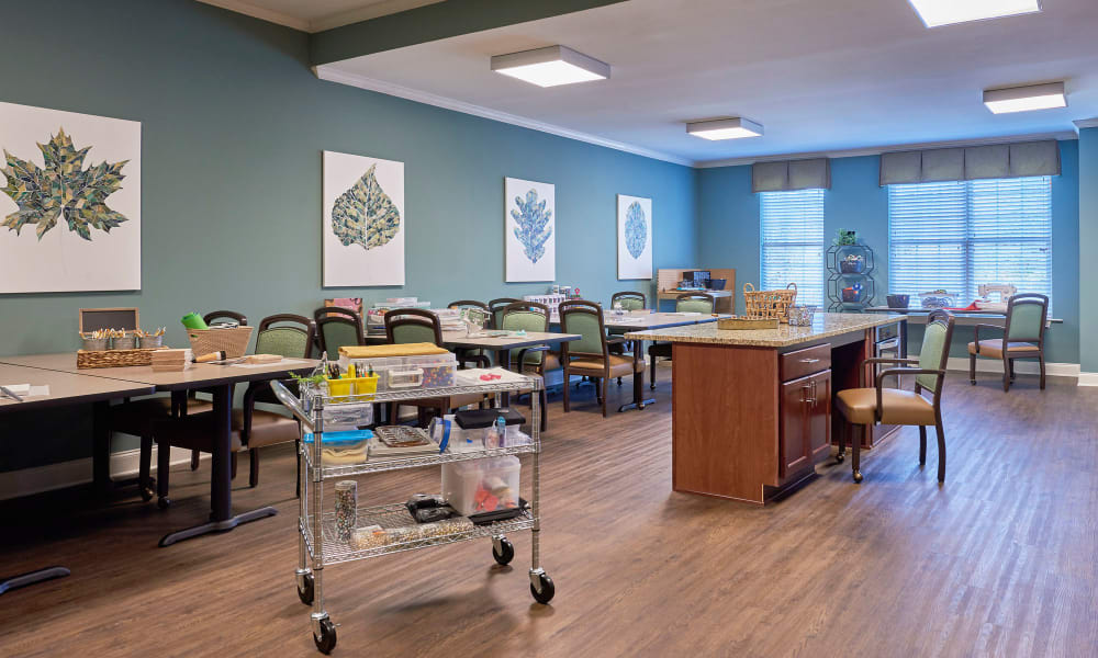 A well-organized classroom with tables, chairs, and a medical cart.